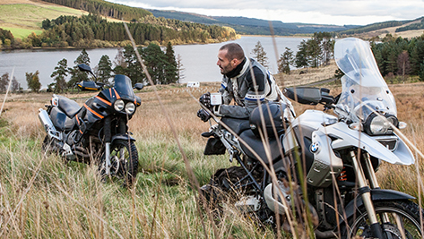 een man zit in het gras te genieten van zijn pauze met het motorrijden